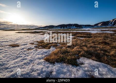 Bella luce notturna su un campo di neve all'alba con montagne sullo sfondo, accanto alla Route 365 tra Laugarvatn e Thingvellir, Islanda Foto Stock