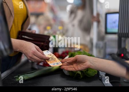 Primo piano della donna che dà denaro al banco cassa del supermercato Foto Stock