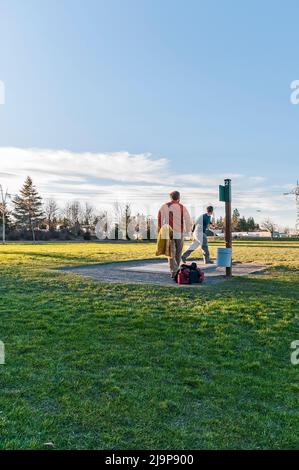 Persone che giocano a disc golf presso il campo da golf Orchard Park Disc, Hillsboro, Oregon. Un disco è nell'aria. Foto Stock