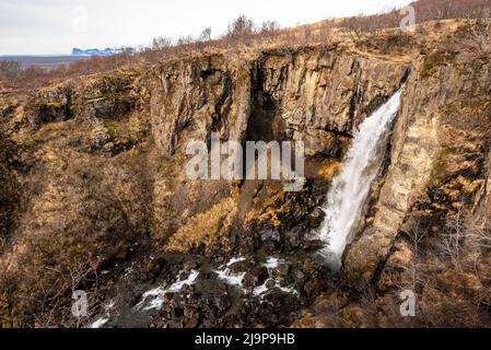 Paesaggio panoramico di fine inverno presso la cascata Hundafoss, dove il fiume Stórilækur si tuffa in una gola nella riserva naturale Skaftadell, Islanda Foto Stock