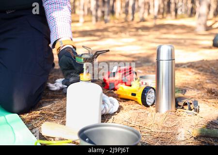 Turista maschio con bruciatore portatile a gas in foresta Foto Stock