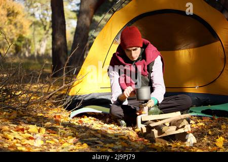 Cibo da cucina turistico maschile su bruciatore a gas portatile in foresta Foto Stock