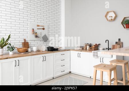 Interno di cucina leggera con banconi, utensili e sgabelli Foto Stock