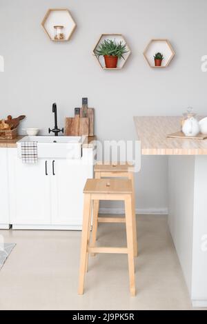 Interno di cucina leggera con banconi, utensili e sgabelli Foto Stock