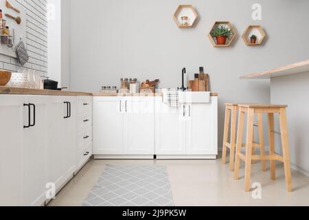 Interno di cucina leggera con banconi, utensili e sgabelli Foto Stock