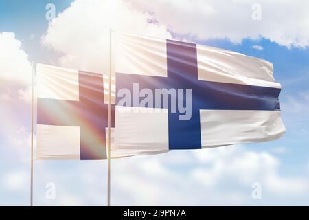 Cielo azzurro soleggiato e bandiere di finlandia e finlandia Foto Stock