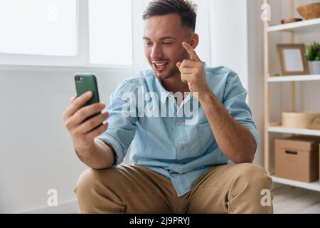 Allegro sorridente ragazzo comunicativo parlare con la famiglia utilizzando la videochiamata telefonica discute le ultime notizie piacevole alzare dito verso l'alto guarda lo schermo Foto Stock