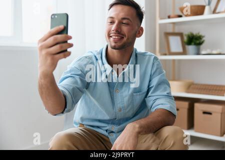 Felice carino gioioso parlare con un amico utilizzando telefono videochiamata discute le ultime notizie piacevole sollevare sorrisi guarda lo schermo. Comunicazione a distanza Foto Stock