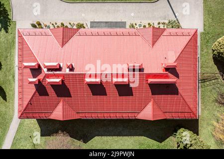 veduta aerea della casa con tetto in pendenza in metallo ondulato rosso, camini e tubi di ventilazione Foto Stock