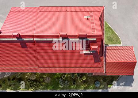vista dell'edificio industriale dall'alto. tetto in metallo rosso con tubi installati di sistemi di ventilazione. Foto Stock