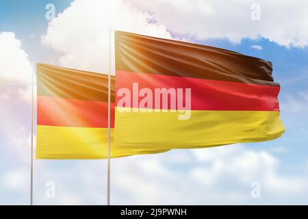 Cielo azzurro soleggiato e bandiere di germania e germania Foto Stock