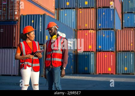 Due ingegneri afroamericani maschi e femmine che parlano e controllano la scatola di carico contenitori da carico nave Cargo per l'esportazione di importazione. Spedizione in banchine Foto Stock