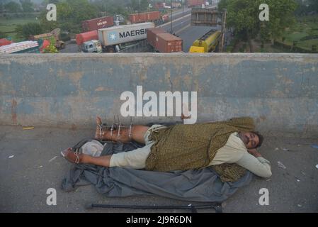 25 maggio 2022, Lahore, Punjab, Pakistan: I pendolari e i conducenti pakistani che dormono nel loro veicolo su un ponte sul fiume Ravi lungo una strada parzialmente bloccata da container da autorità locali per ostacolare la mobilità prima del sit-in pianificato ad Islamabad dall'ex primo ministro pakistano del partito Tehreek-e-INSAF (PTI), Imran Khan, a Lahore. Il principale partito di opposizione del Pakistan, guidato dal primo ministro recentemente estromesso Imran Khan, ha accusato la polizia di aver detenuto centinaia di suoi sostenitori in incursioni iniziate all'inizio di martedì Foto Stock