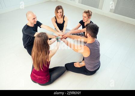 un gruppo felice di persone di uomini e donne che praticano lo yoga in studio. gruppi di meditazione, comunicazione classe yoga. il concetto di gruppo Foto Stock