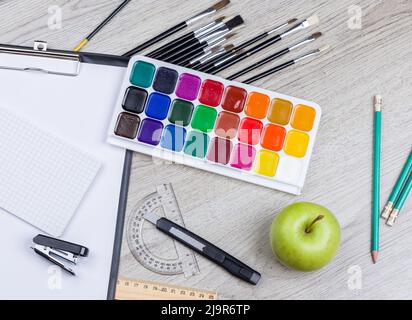 Torna a scuola nota libro, matite, Lope, mela verde su tavola di legno Foto Stock