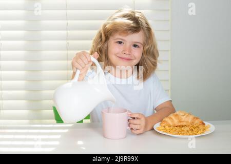 Pretten bambino versando latte intero di mucche. Ragazzo che mangia verdure alimentari sane. Colazione con latte, frutta e verdura. I bambini mangiano durante il pranzo Foto Stock