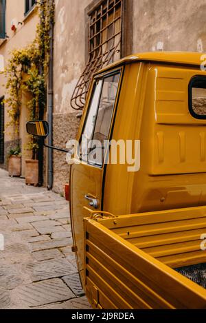 Un tipico tre ruote italiano nelle strette viuzze medievali di Castiglione della Pescaia, un antico borgo sulla costa toscana Foto Stock