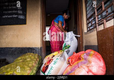 24 maggio 2022, Tehatta, Bengala Occidentale, India: Il governo del Bengala Occidentale ha diretto le scuole di governo di stato a distribuire le forniture di pasto di metà giorno ai genitori degli allievi durante le vacanze di estate in modo che i bambini bisognosi non siano privati del programma. L'avviso ha detto che ogni studente avrebbe ottenuto 2 kg di riso, 2 kg di patate, 250 grammi di zucchero, 250 grammi di legumi, e una saponetta. Così gli studenti sono venuti in una scuola elementare per ottenere i loro prodotti alimentari durante le vacanze estive e alcuni di loro stanno anche aiutando a dare gli articoli alimentari a Nabin Nagar, West Bengala. (Credit Image: © Soumrabyata Roy/Pacific Foto Stock