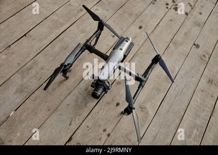 Un drone professionale si erge su un pavimento in legno, preparandosi per il volo, dall'alto Foto Stock