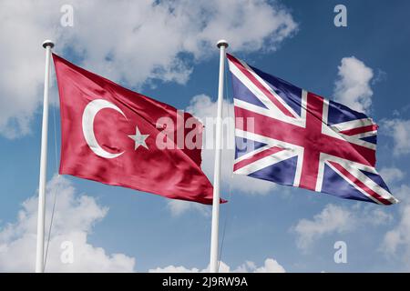 Turchia e Regno Unito due bandiere su flagpoli e sfondo blu cielo nuvoloso Foto Stock