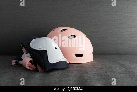 Casco rosa su sfondo grigio scuro. Protezione di sicurezza per attività esterne dei bambini Foto Stock