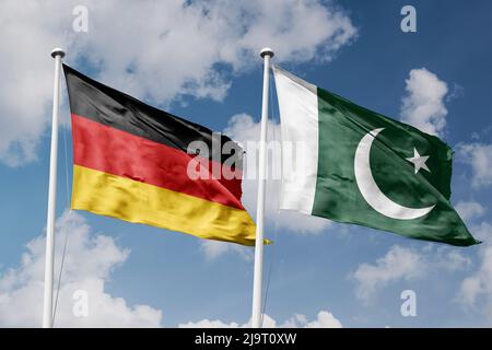 Germania e Pakistan due bandiere su flagpoli e sfondo blu cielo nuvoloso Foto Stock