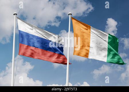 Russia e CTE d'Avorio due bandiere su flagpoli e sfondo blu cielo nuvoloso Foto Stock