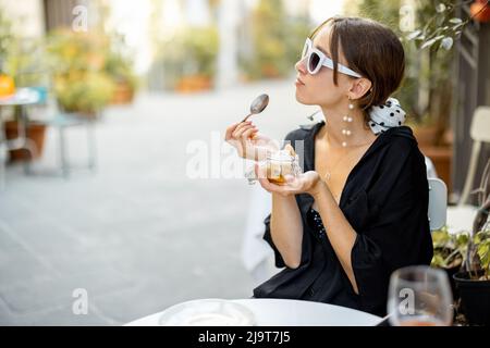 Donna che mangia il dessert tiramisù al ristorante all'aperto Foto Stock
