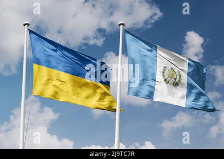 Ucraina e Guatemala due bandiere su paletti e blu nuvoloso sfondo del cielo Foto Stock