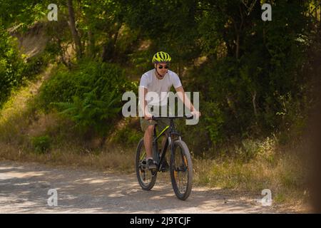 Il bicyclist bello e adatto sta guidando la sua bicicletta mentre cerca di tenersi al passo con il gruppo Foto Stock