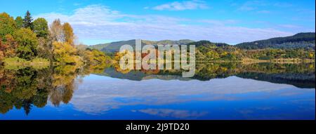 Alberi autunnali e nuvole si riflettono nelle acque del bellissimo lago Tutira nella regione di Hawke's Bay, Nuova Zelanda Foto Stock