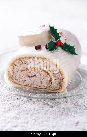 Torta di legno di yule al cioccolato bianco con ornamento su tavola di legno e neve Foto Stock