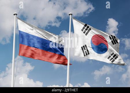 Russia e Corea del Sud due bandiere su flagpoli e sfondo blu cielo nuvoloso Foto Stock