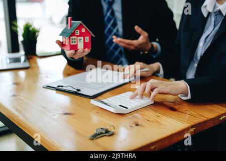 L'agente immobiliare sta spiegando lo stile della casa ai clienti che vengono a contatto per vedere il disegno della casa e l'accordo di acquisto, ipoteca Foto Stock