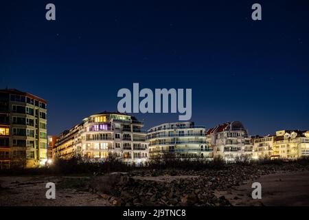 Località balneare tranquilla città di Pomorie con luci elettriche luminose e grandi e confortevoli hotel di lusso sullo sfondo di notte stellato blu cielo e ca Foto Stock