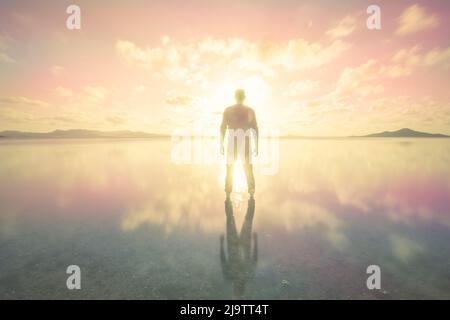 Silhouette di un uomo sopra il tramonto colorato e rosa delle acque calme del Mar Menor nella regione di Murcia Foto Stock