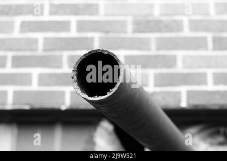 Vecchio tubo arrugginito che sporge dal muro in bianco e nero. Foto Stock