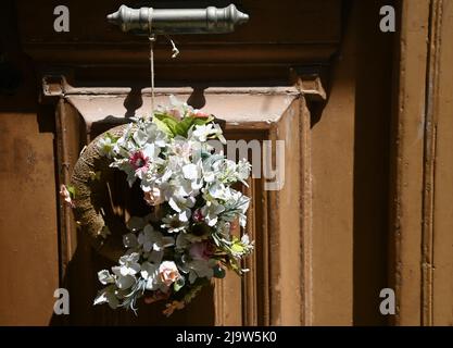 Vecchia casa neoclassica antica porta d'ingresso in legno con una maniglia in ottone retrò e un appeso fiori secchi maggio corona. Foto Stock