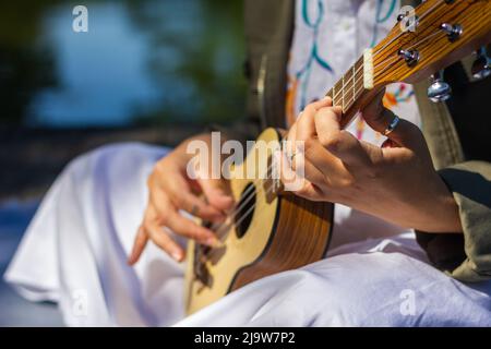 Donna che impara a giocare all'aperto ukulele. Divertimento di musica Foto Stock