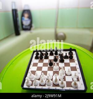 L'amante degli scacchi ama il debutto di Reti in una vasca idromassaggio, mescolando delizie fisiche e intellettuali, scacchi mazzo in cima a una ciotola di plastica verde capovolta Foto Stock