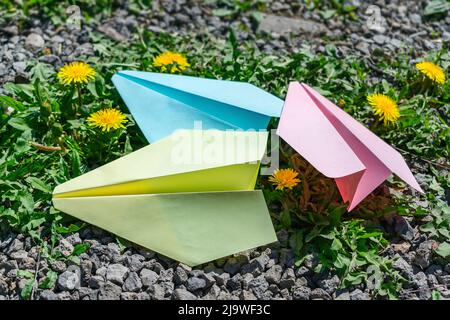 Aeroplani multicolore per bambini piegati dalla carta sull'erba Foto Stock