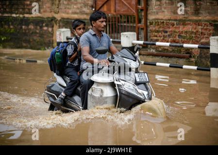 Guwahati, Assam, India. 25th maggio 2022. Un uomo ritorna suo figlio in scooter che attraversa una strada allagata dopo forti piogge, a Guwahati, Assam, India, il 25 maggio 2022. Il waterlogging è una scena comune nella città di Guwahati a causa del sistema di drenaggio povero. Credit: David Talukdar/Alamy Live News Foto Stock