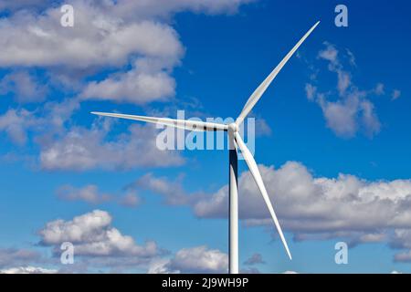 Mulino contro un cielo azzurro e nuvole bianche. Fonte di energia elettrica ecocompatibile Foto Stock