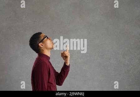 L'uomo sorpreso isolato su uno sfondo di spazio copia punta il suo dito in su come pensa ad un'idea Foto Stock