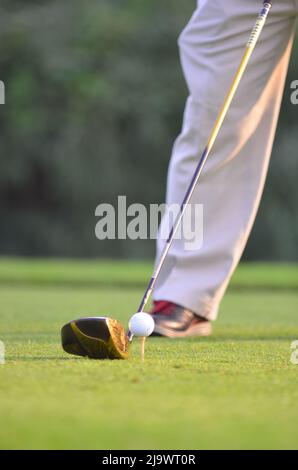 Scatto corto del golfer maschio che ottiene pronto colpire la sfera di golf sul tee. Foto Stock