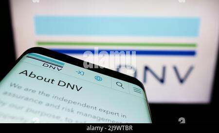 Smartphone con sito Web della società di servizi norvegese DNV SULLO schermo di fronte al logo aziendale. Mettere a fuoco sulla parte superiore sinistra del display del telefono. Foto Stock