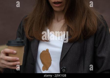 Macchie sporche di caffè versato mentre si cammina per lavorare su abbigliamento donna. Il concetto di pulizia delle macchie sui vestiti Foto Stock