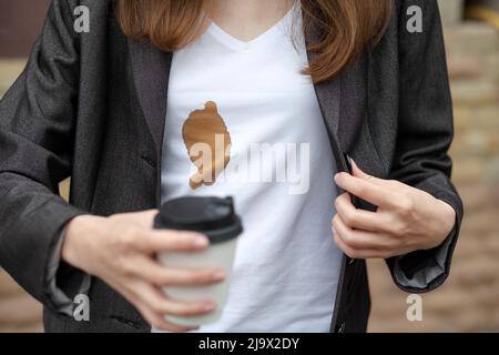 Macchie sporche di caffè versato mentre si cammina per lavorare sulla camicia bianca da donna. Il concetto di pulizia delle macchie sui vestiti Foto Stock