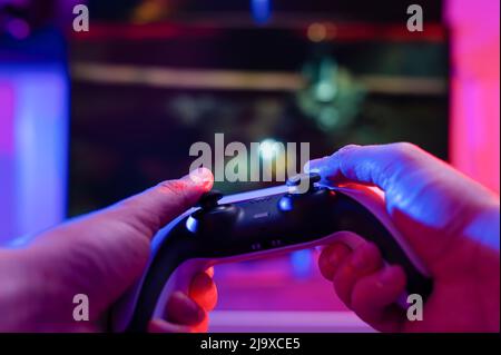 Gamepad nelle mani di un giocatore su un background tecnologico. Gioca a videogiochi online con gli amici. Passatempo divertente, giochi d'avventura, cultura giovanile. Clo Foto Stock