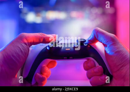 Primo piano di un gadget moderno - gamepad. Un videogamer gioca online con gli amici su un grande schermo TV. Strategia di gioco, realtà virtuale, cyberspazio, e Foto Stock